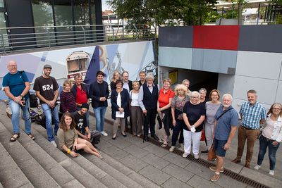 Der Vorstand des Partnerschaftsvereins mit Bürgermeister Mario Dahm und den Künstlern an der Wand der Partnerstädte