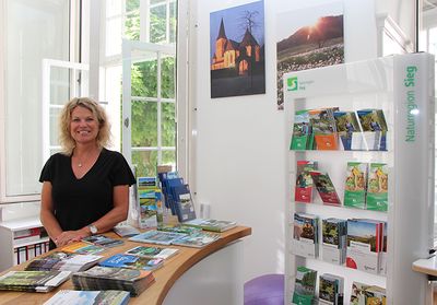 Die Tourist-Info der Stadt Hennef hat wieder geöffnet. Caroline Overath, Mitarbeiterin der Tourist-Info, berät rund um den Tourismus in Hennef (der Mundschutz wurde kurz für das Foto abgenommen).